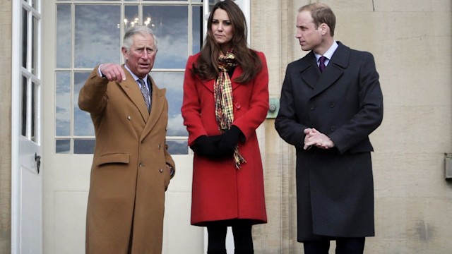 King Charles frowning and pointing while Princess Kate and Prince William listen on steps