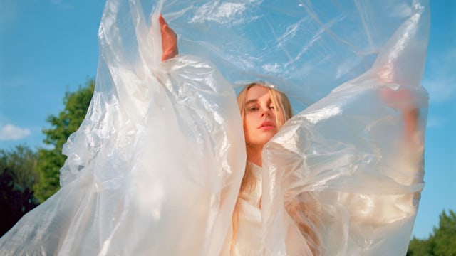 Portrait of young woman making dance performance with light transparent plastic film. She has long blond hair. Shot on medium format film camera