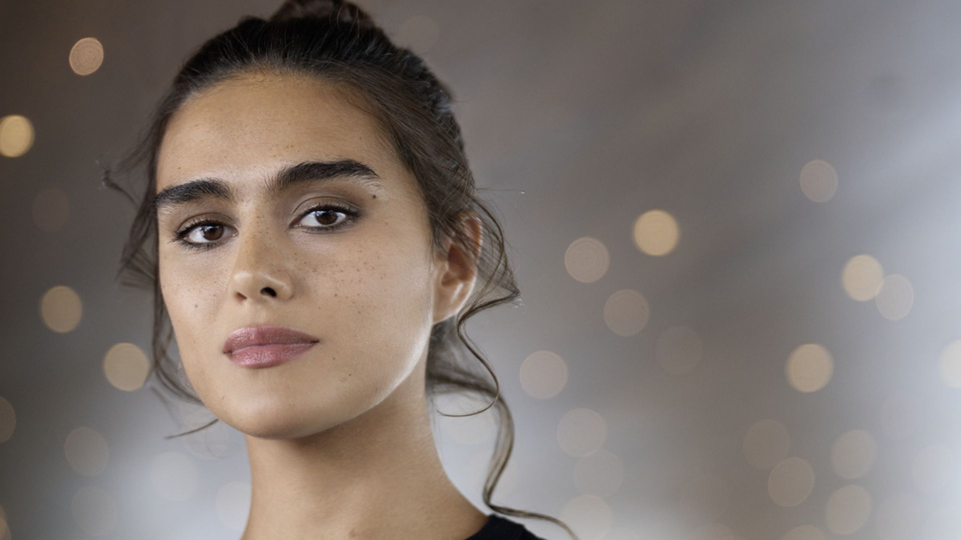 Chanel model with natural makeup and her hair in a messy bun 