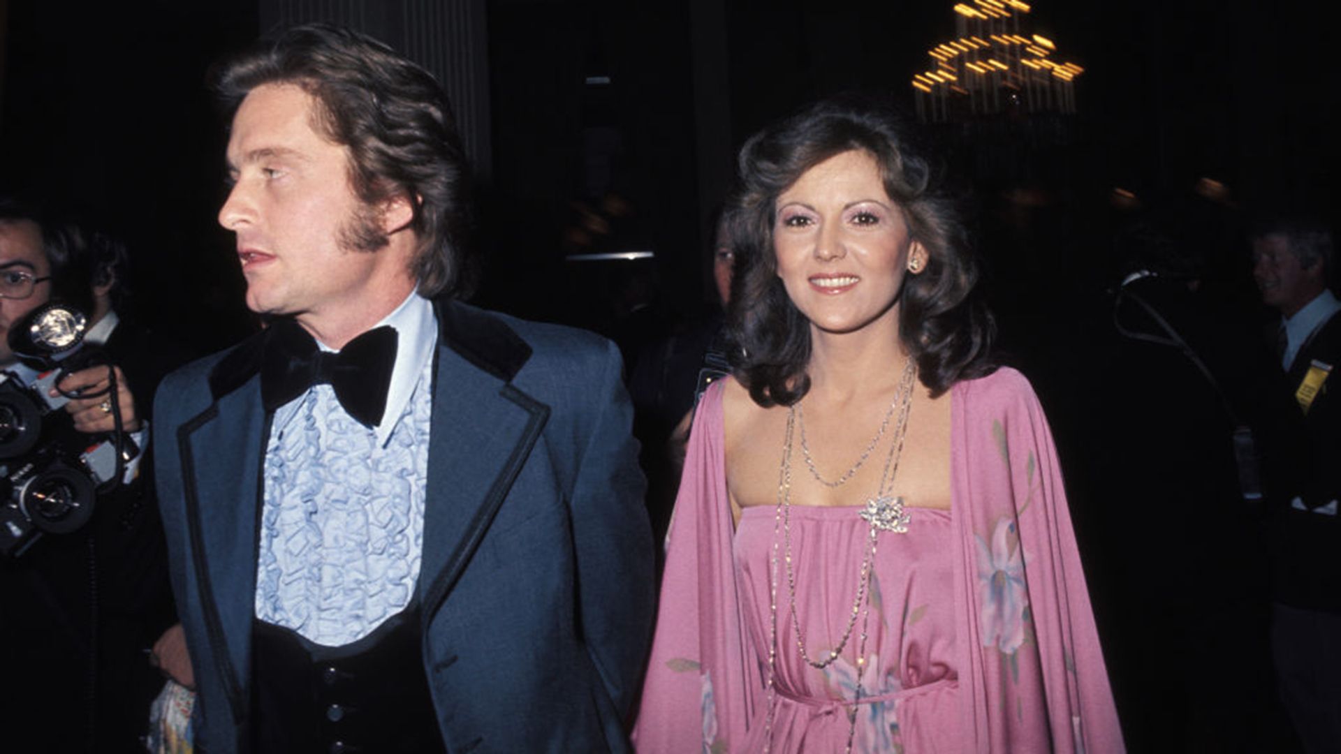 Michael Douglas in a blue tuxedo and Brenda Vaccaro in a pink dress 