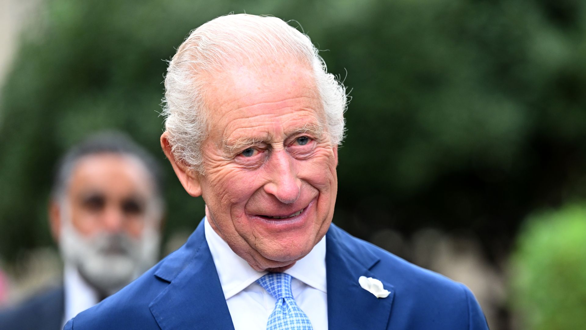 King Charles smiling in a blue suit