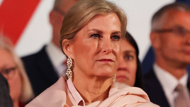 Duchess Sophie in a pink coat and gold earrings looking solemn