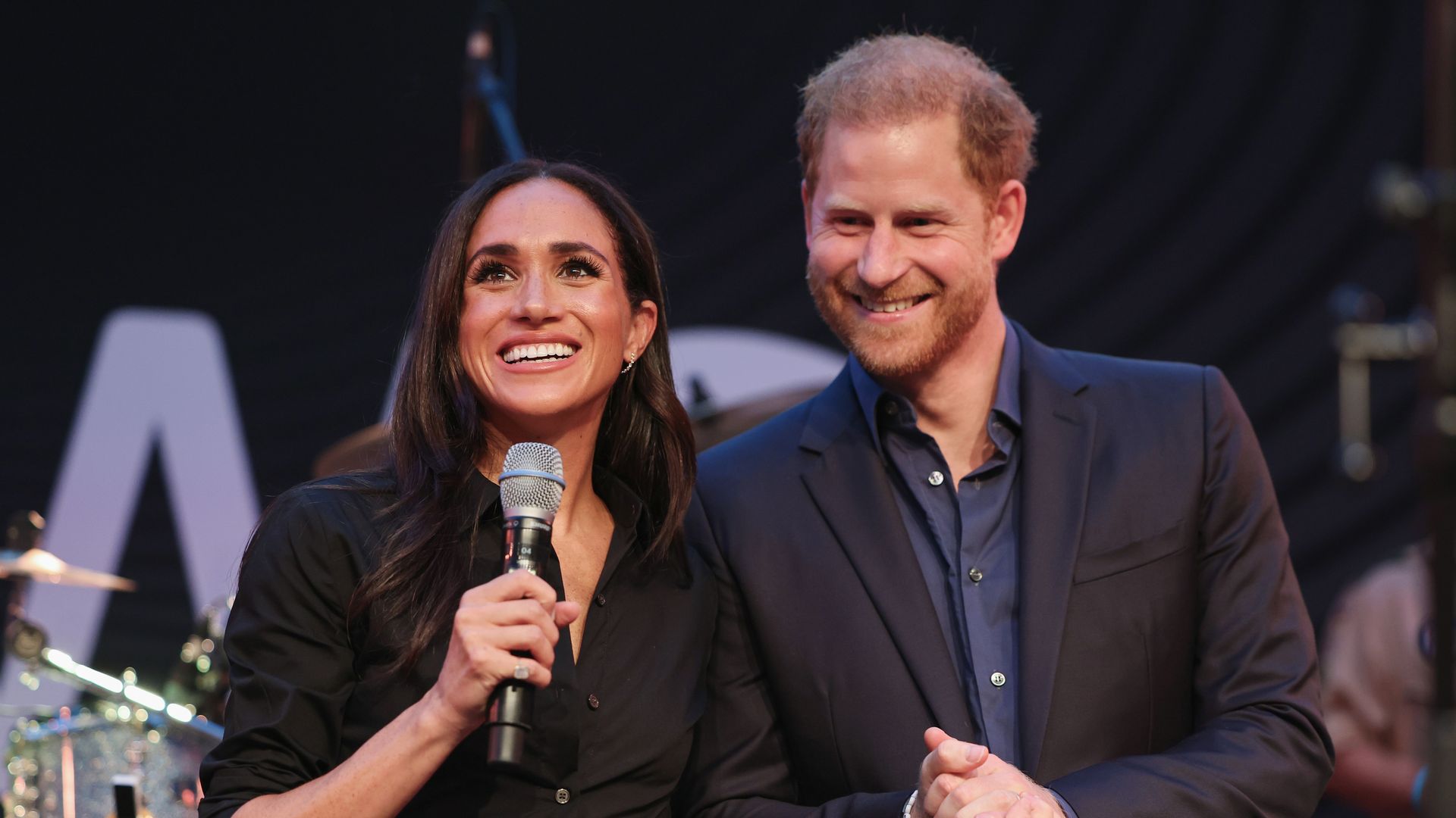 Meghan Markle holding microphone with Prince Harry