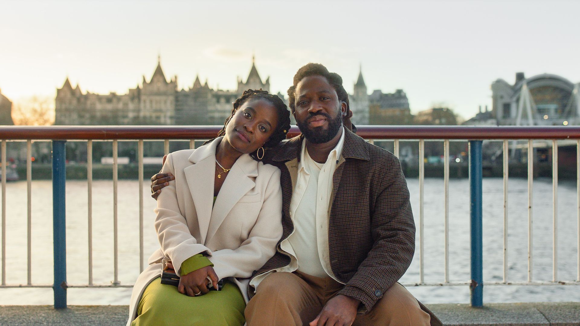 woman and man sitting on bench next to river