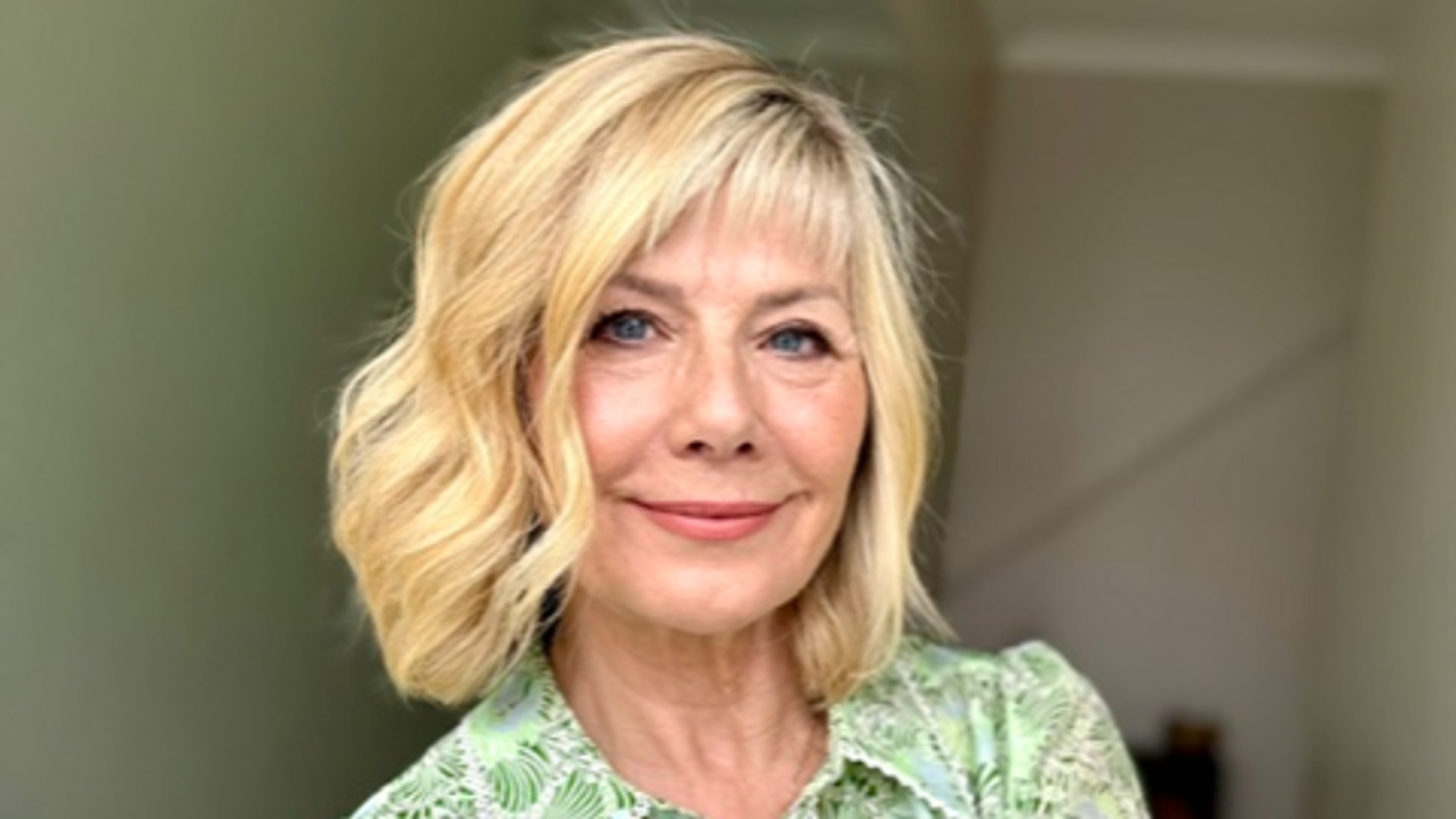Smiling blonde woman in a printed green shirt