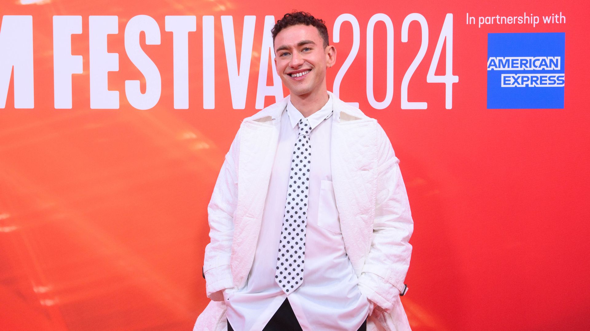 Olly Alexander in a white outfit and spotted tie