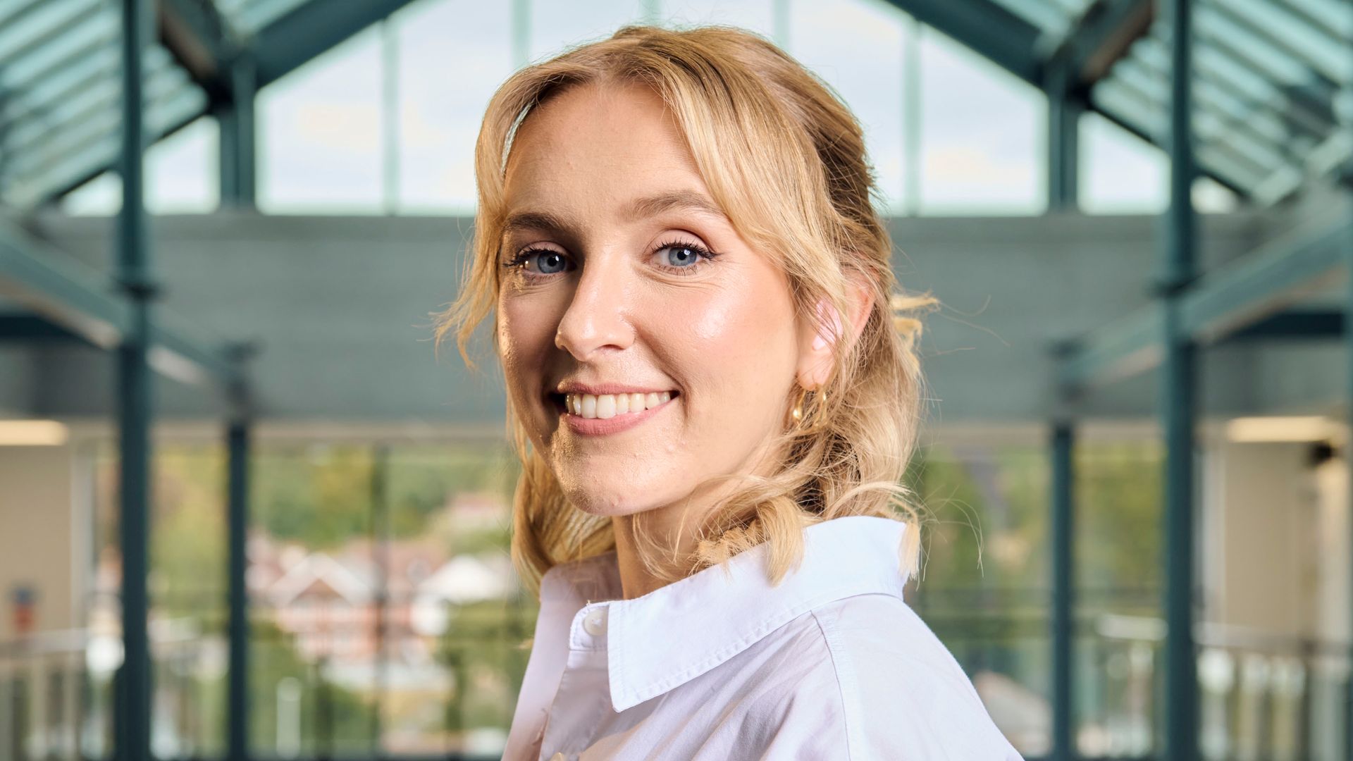Blonde woman in white shirt smiling at camera