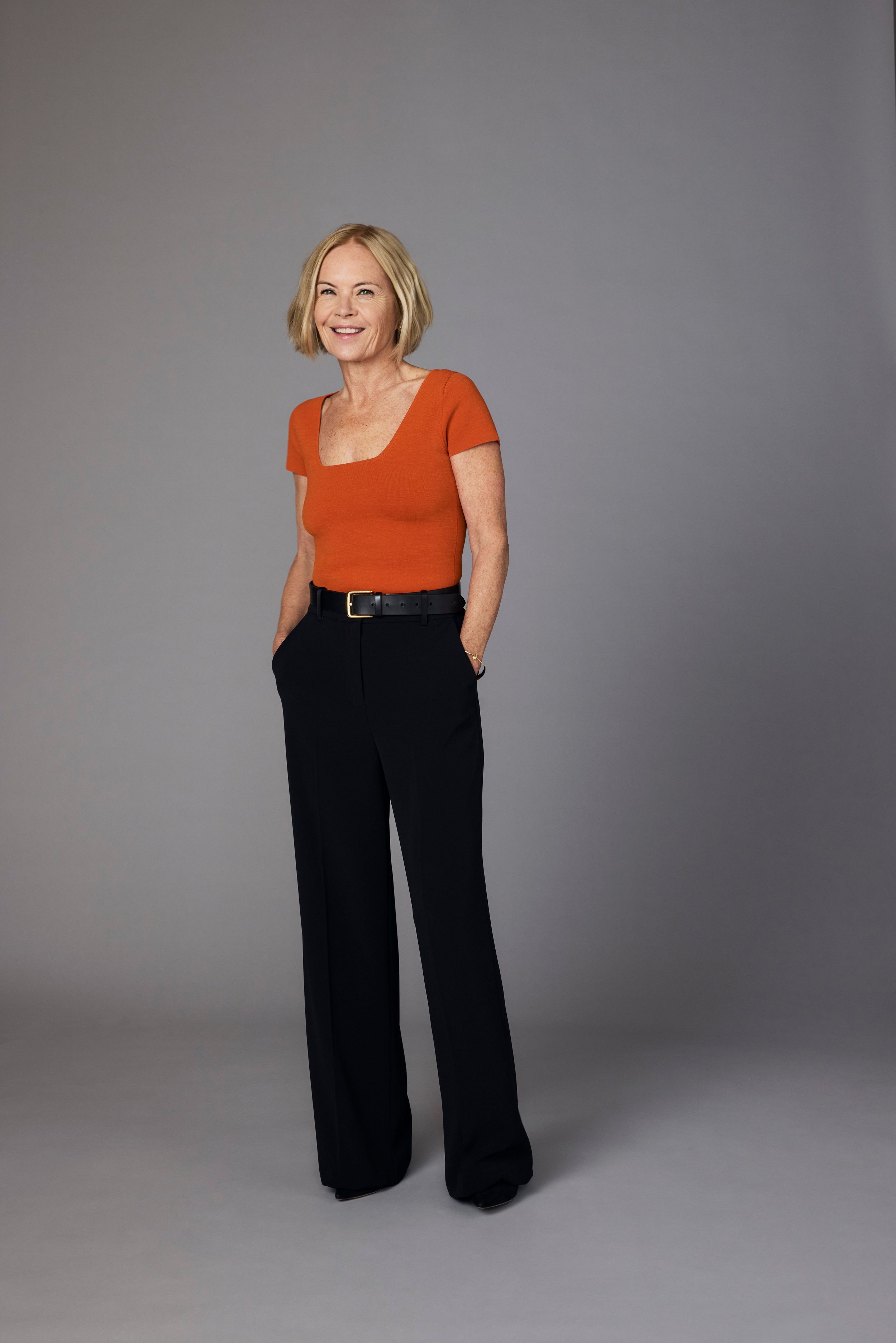 woman in black trousers and a red top with her hands in her pockets 