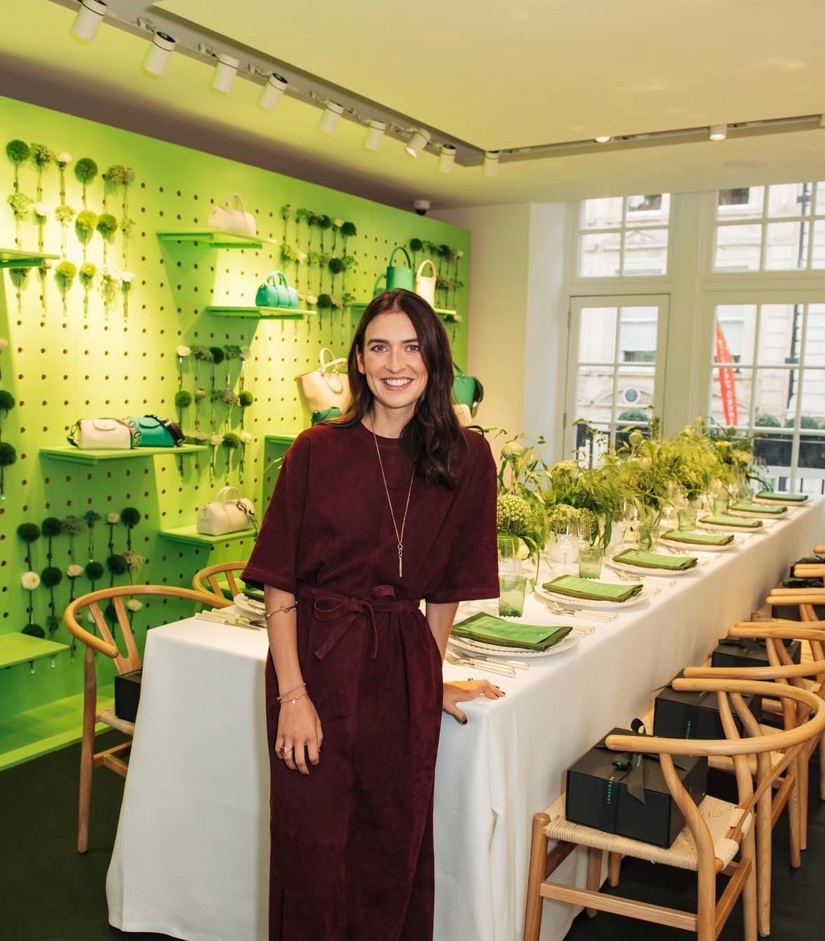 Juliette stuns in a burgundy suede belted midi dress with short sleeves, accessorized with a delicate necklace and soft waves, exuding minimalist sophistication.​