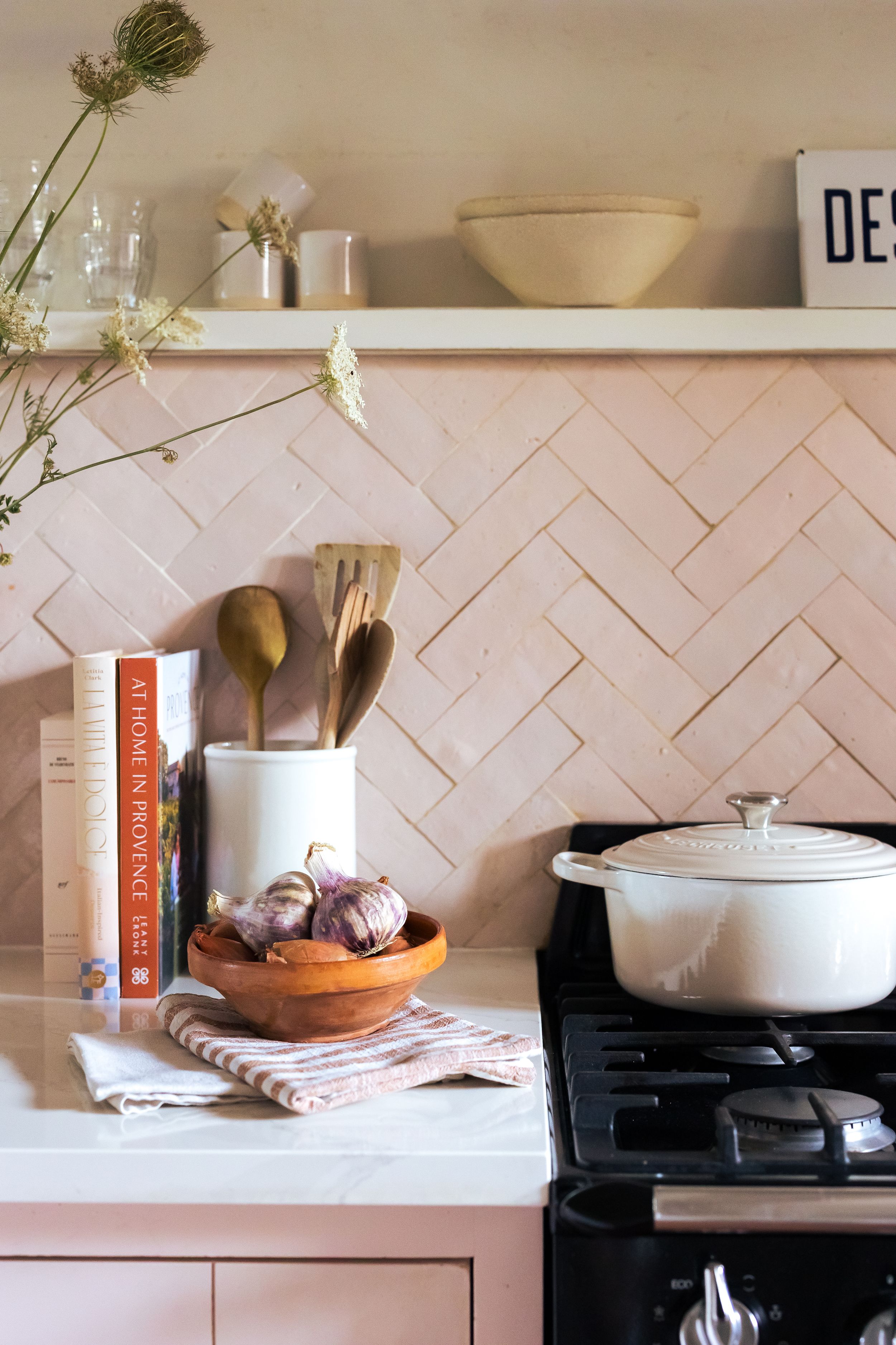The countertop in the pink-tiled kitchen with a casserole sized dish on the cooker in Domaine Mirabeau Provençal manor house,