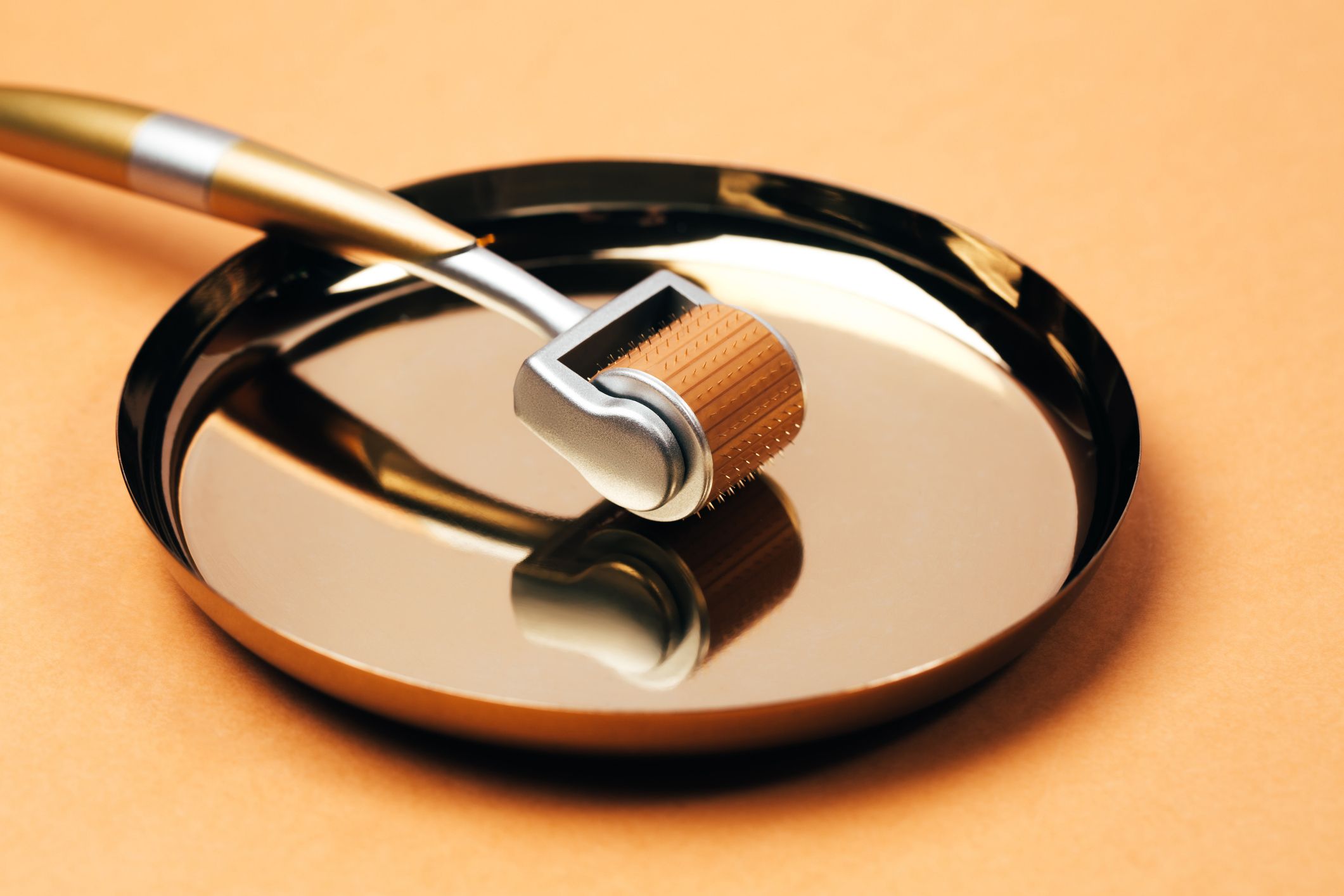 Pourquoi la « saison de préparation tranquille » est la période la plus importante de l'année pour votre routine beauté 3 Rouleau de massage en métal argenté-orange avec micro-aiguilles sur fond orange pastel. Concept de traitement dermatologique de différentes affections cutanées. Macrophotographie