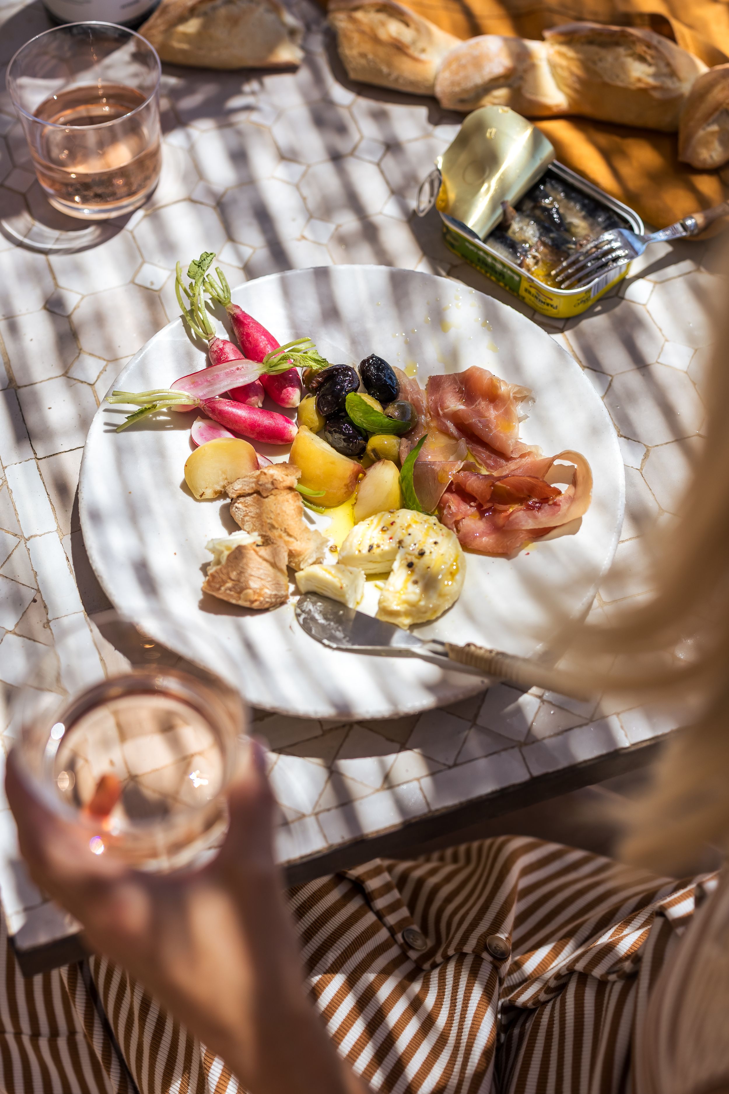 A plate of continental food with a glass of rose on the side in the garden of Domaine Mirabeau Provençal manor house
