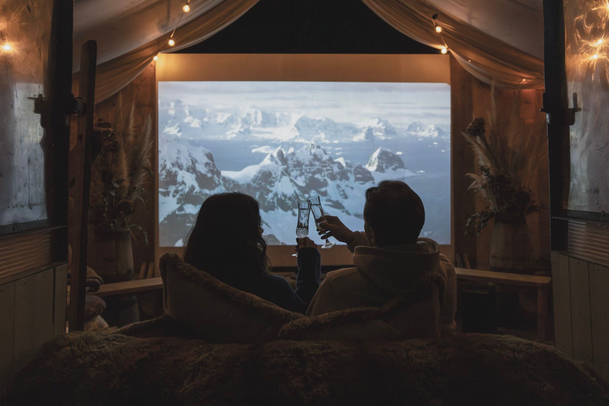 two people holding champagne flutes in front of cinema screen