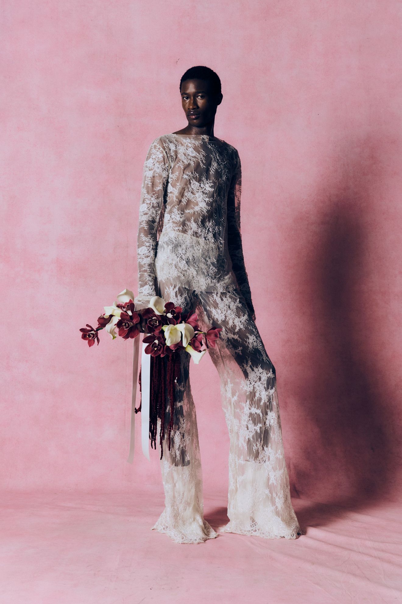 Du drame vintage au nouveau minimalisme, les plus grandes tendances de LFW AW26 9 Un mannequin porte un haut en dentelle transparente et un pantalon évasé en dentelle et tient un bouquet de fleurs