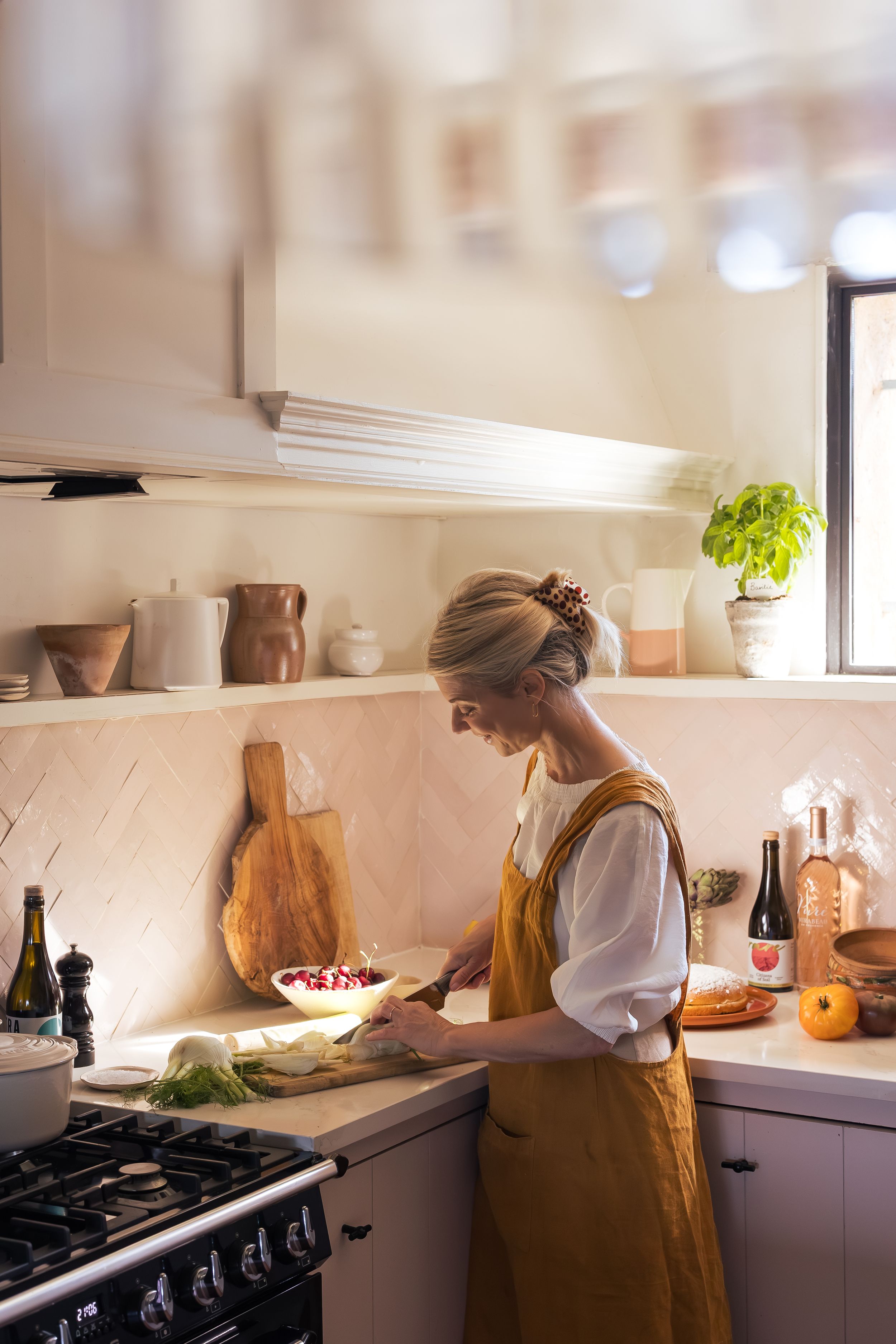 Jeany chopping up vegetables in the kitchen of Domaine Mirabeau Provençal manor house, wearing a mustard apron and white t-shirt