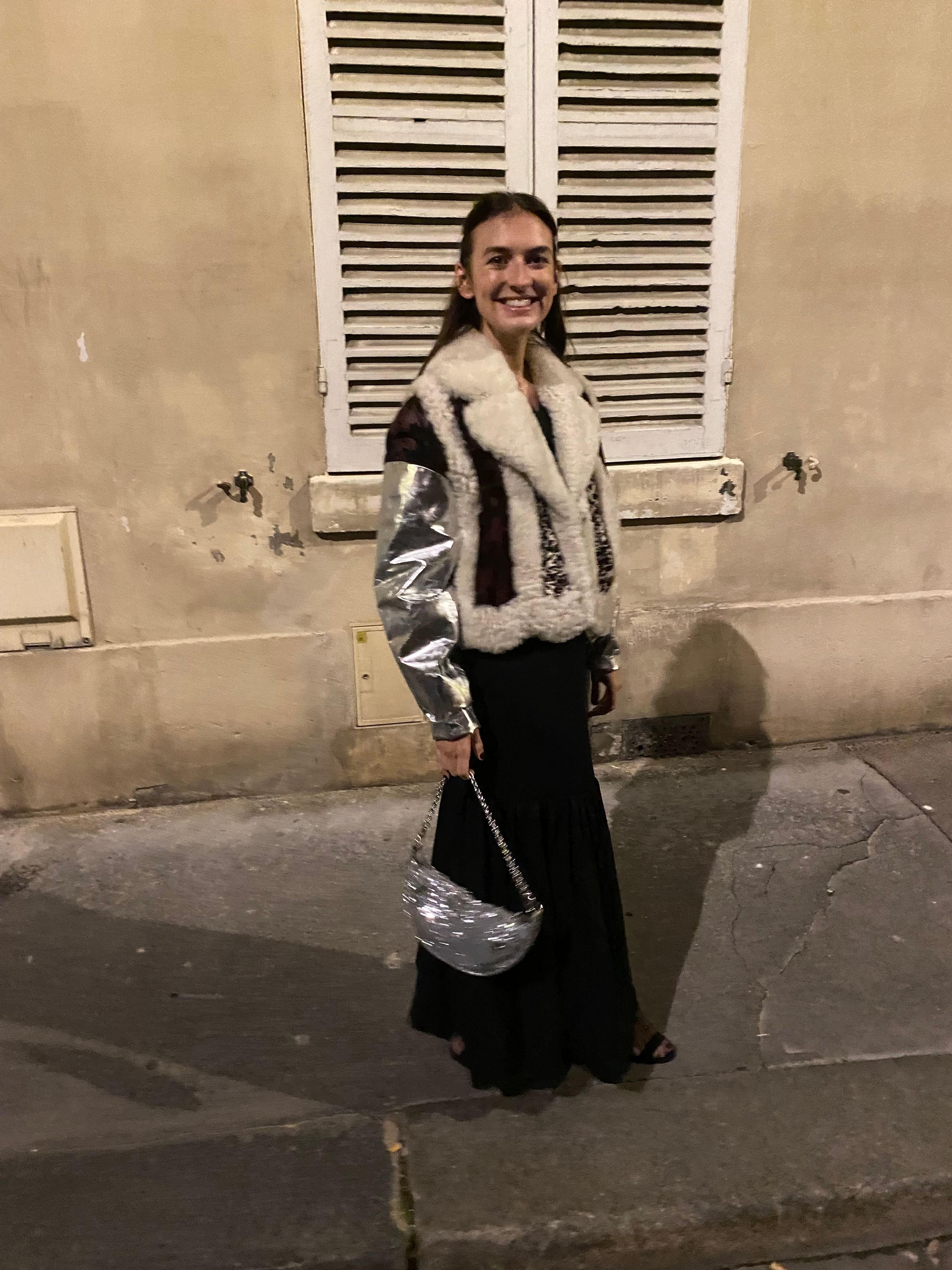 Juliette dazzles in a black maxi dress complemented by a silver-sleeved shearling jacket and a sequined hobo bag, ready for a glamorous night out.​
