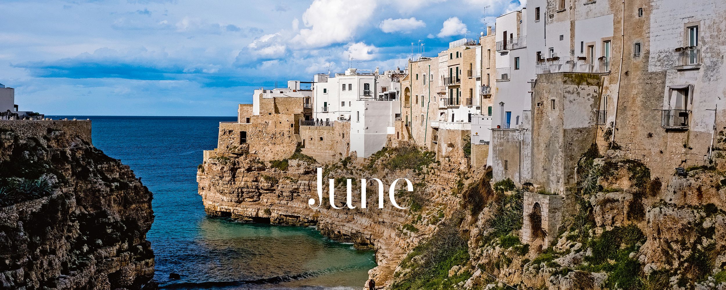 View of white buildings along a cliffside by the sea with a clear blue sky