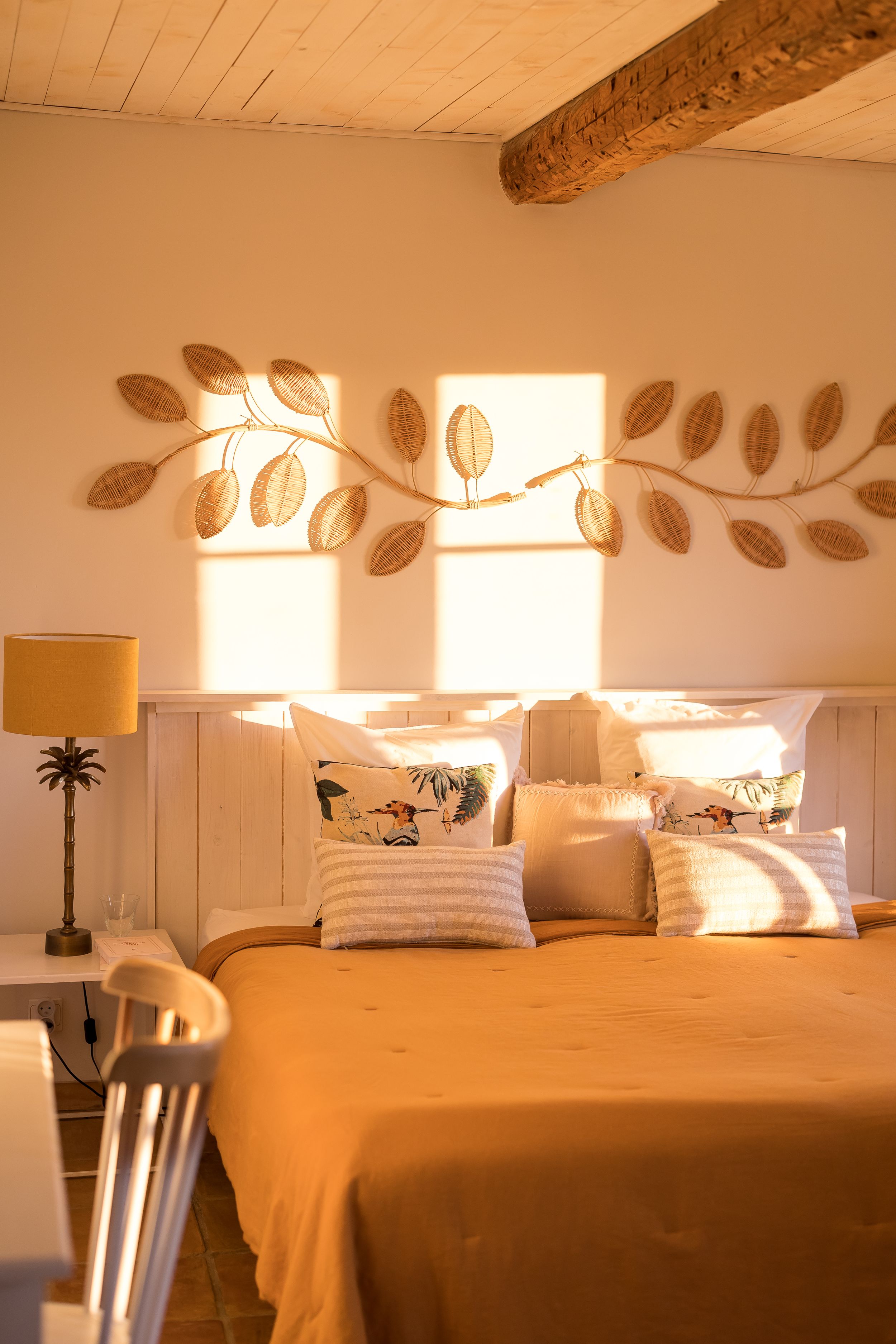 One of the bedrooms in golden hour, with a nature theme and mustard coloured shoot in Domaine Mirabeau Provençal manor house,
