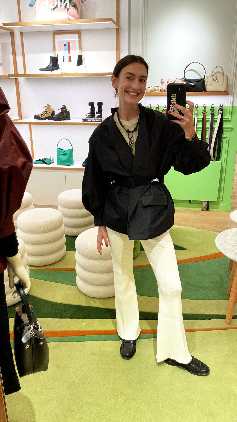 Juliette Poupard Delafontaine wears a black kimono-style jacket over a cream ribbed ensemble, accessorized with a chunky necklace and loafers, exuding effortless Parisian chic.​