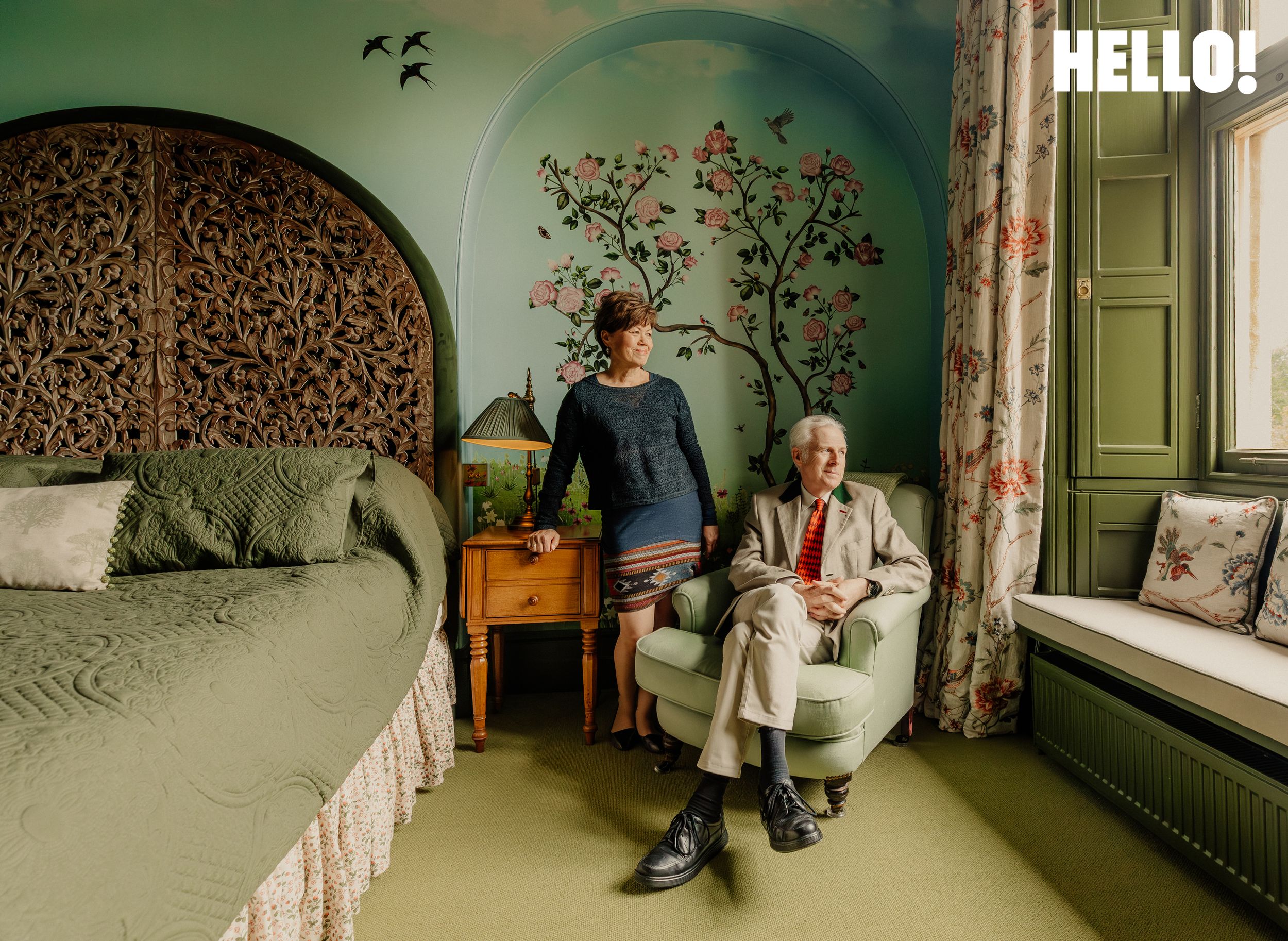 The couple relax in the Meadow Room which includes a large bed and a floral design on the teal walls