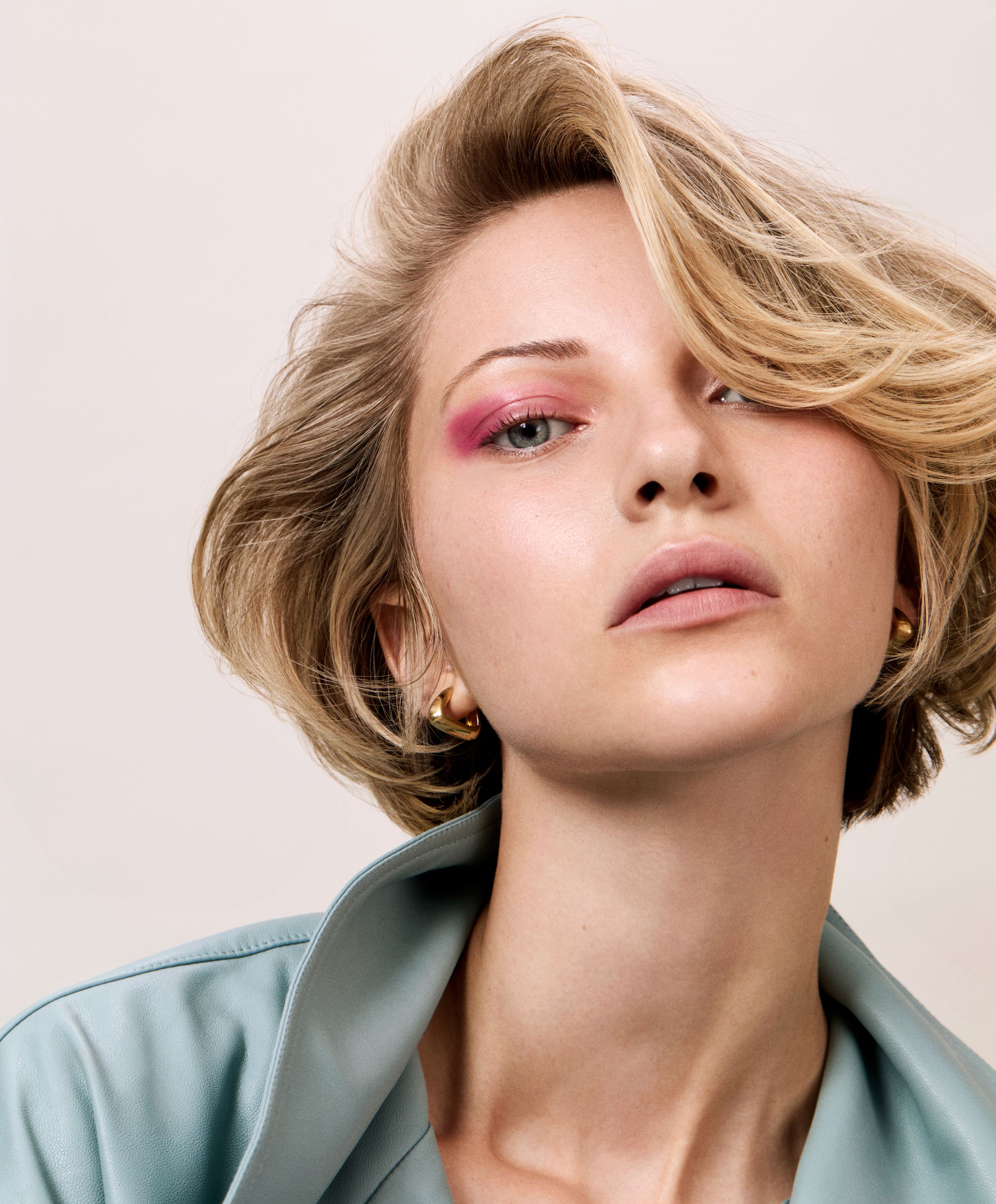 model with blonde side swept hair and bold pink eyeliner