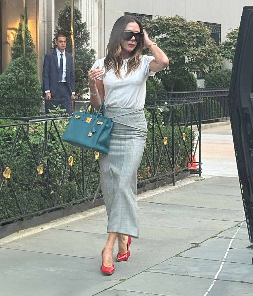 Victoria Beckham pictured in NYC wearing a grey skirt and white t-shirt teamed with red shoes