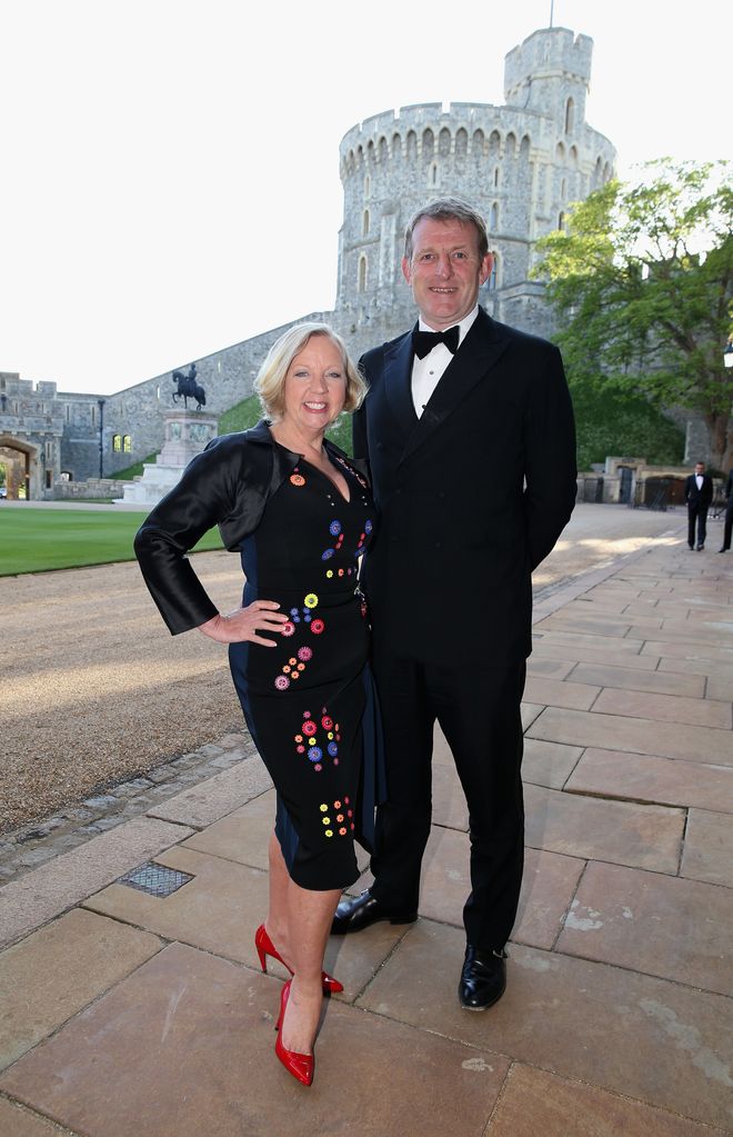 Deborah Meaden in red heels posing outside for a photo with her husband Paul