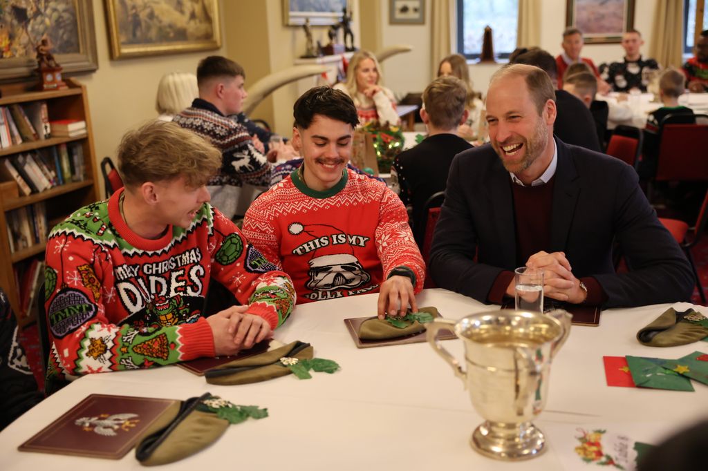 Prince William laughing with two men in Christmas jumpers