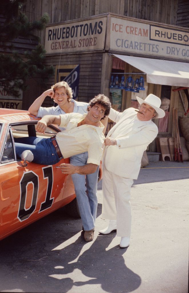 Coy Duke smiles as Vance Duke is dragged out of the 'General Lee' by Jefferson Davis 'Boss' Hogg in a publicity still from the television series 'The Dukes of Hazzard