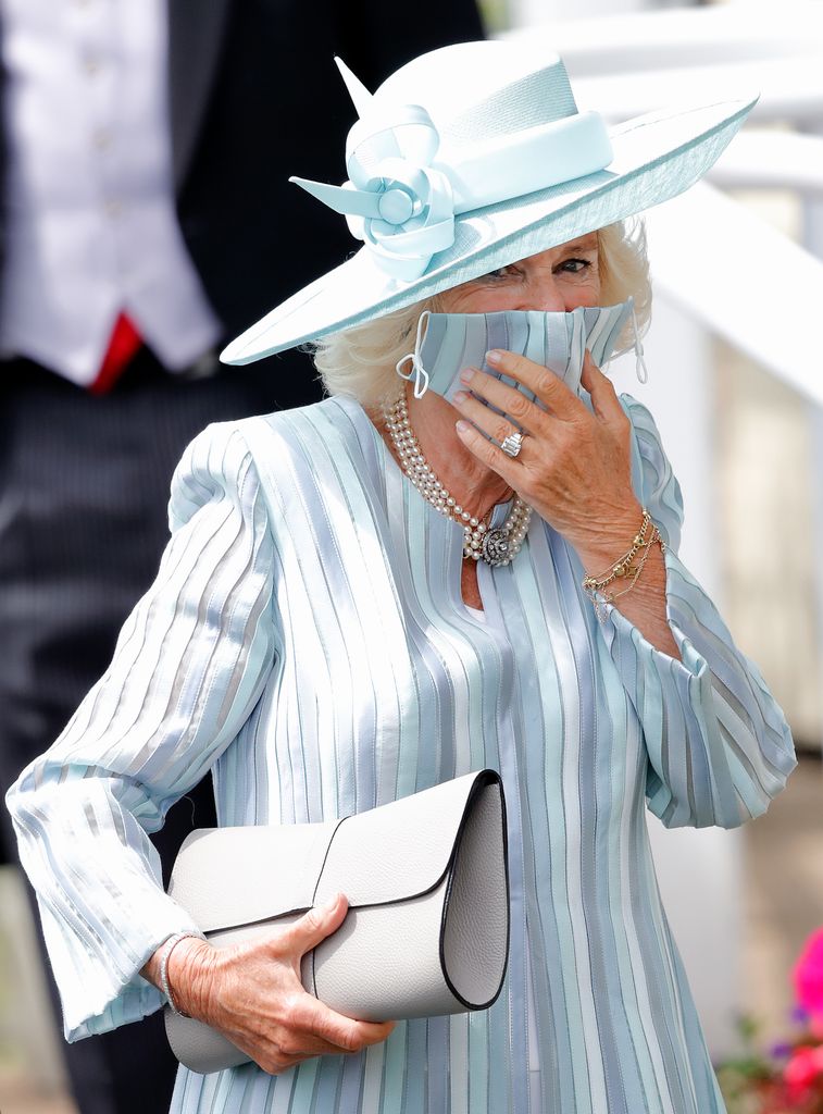 Queen Camilla holding up face mask at Ascot