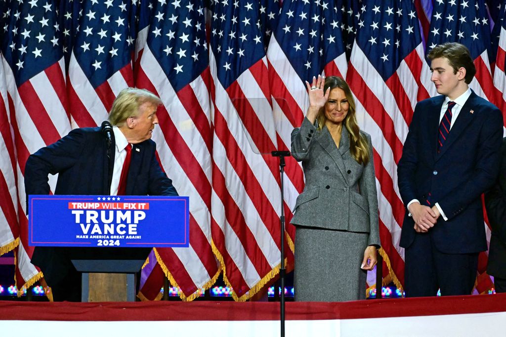 Former US President and Republican presidential candidate Donald Trump acknolewdges former US First Lady Melania Trump (C) alongside their son Barron Trump (R) during an election night event at the West Palm Beach Convention Center in West Palm Beach, Florida, on November 6, 2024.