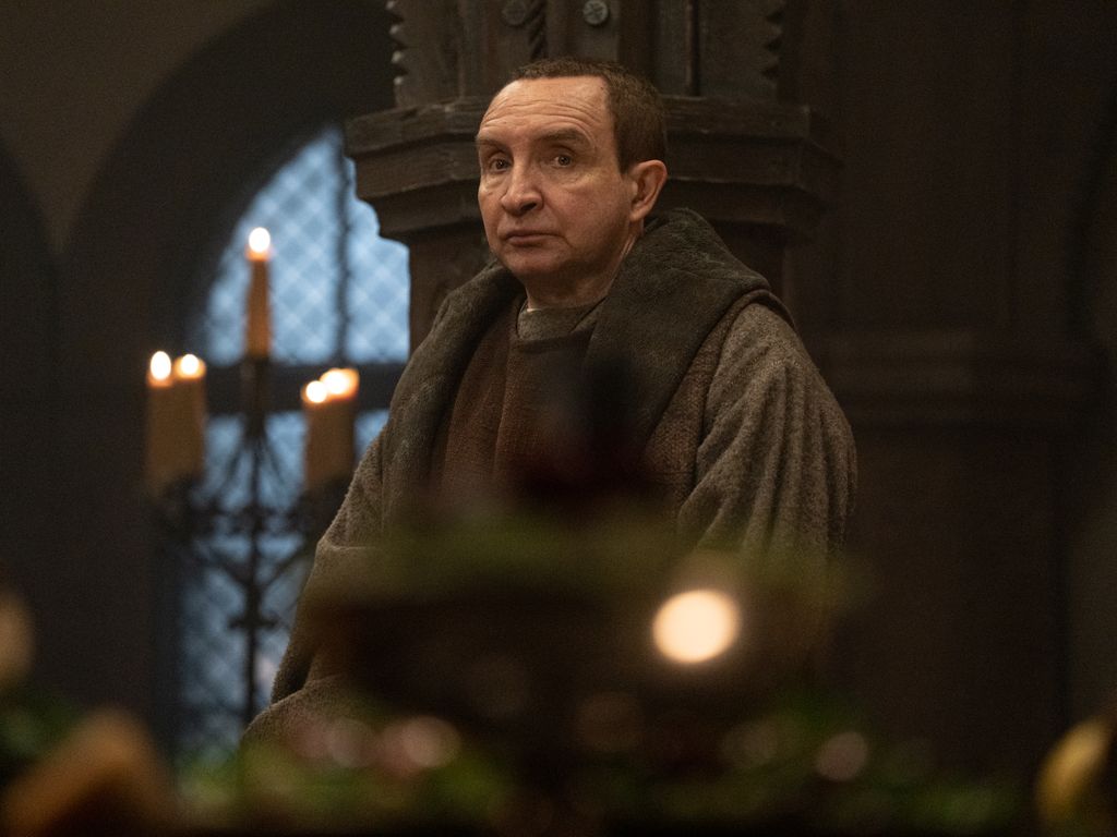 man in period clothing in candle-lit room