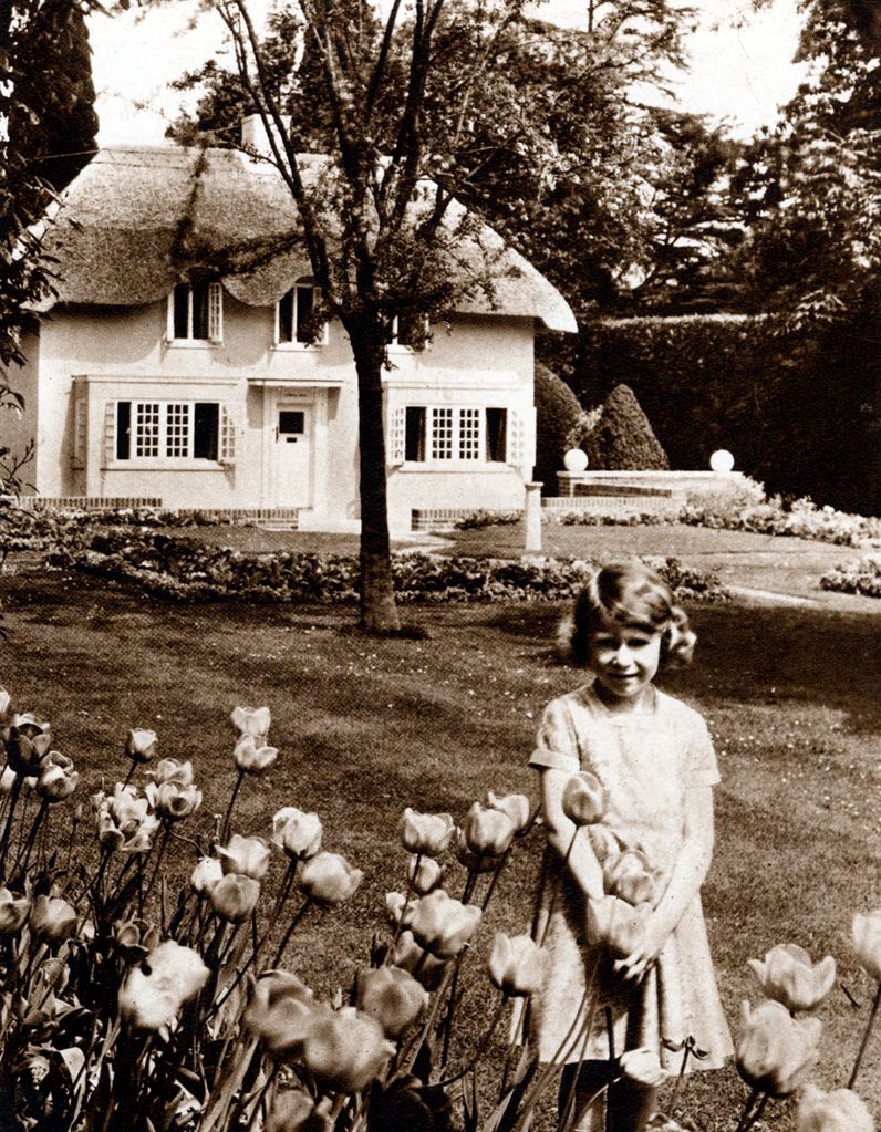 A young Queen Elizabeth standing by Y Bwthyn Bach (The Little House) the playhouse given to her by the people of Wales