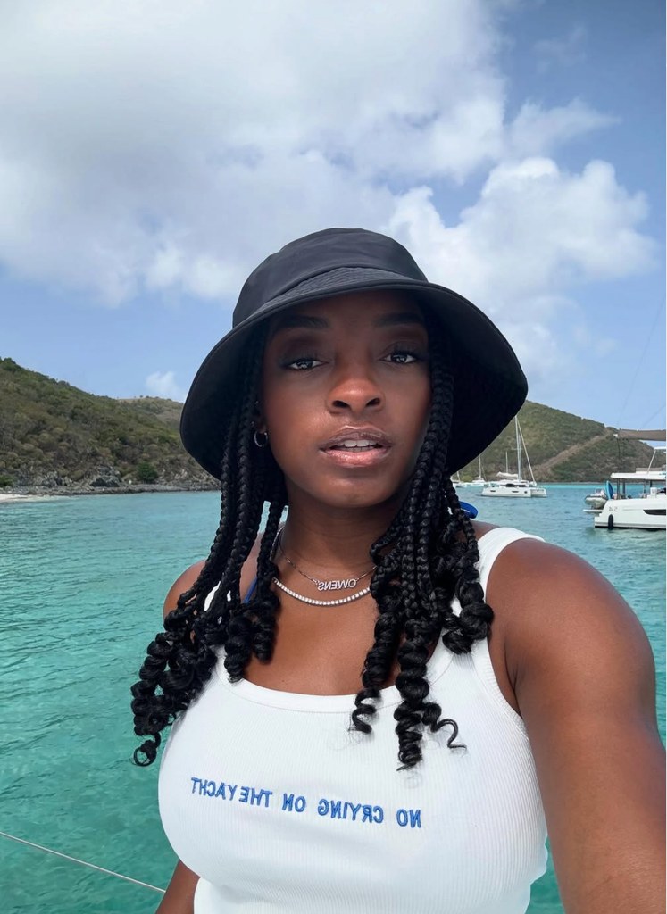 Photo partagée par Simone Biles sur Instagram en juillet 2025 à bord d'un yacht, portant un débardeur blanc et un chapeau de seau noir