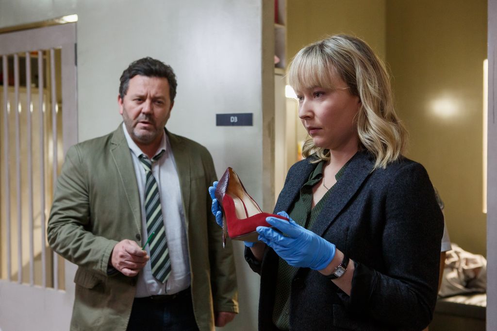 woman holding red stiletto next to man in suit