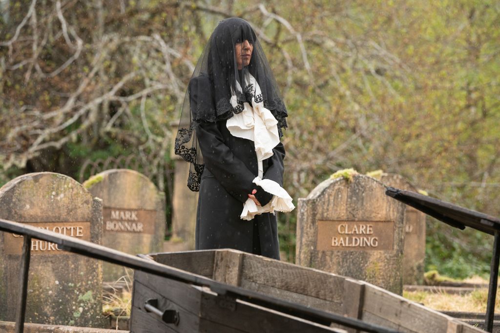 claudia winkleman wearing a black veil, black coat, white frilly blouse on celebrity traitors