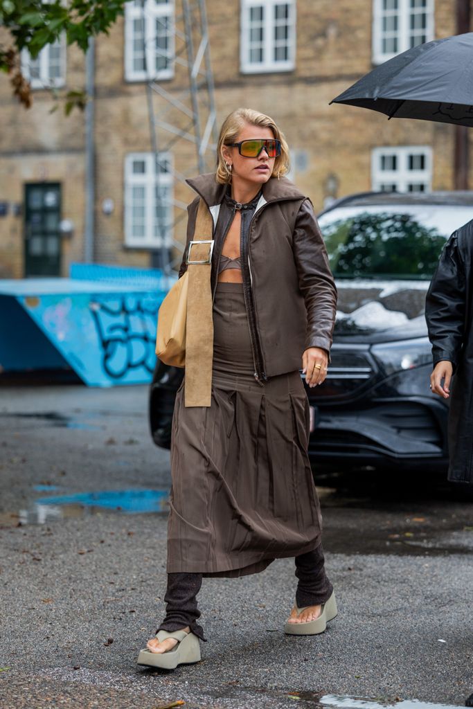  A guest wears high waisted skirt, brown jacket, beige bag, platform sandals outside 7 Days Active during the Copenhagen Fashion Week Spring/Summer 2024 