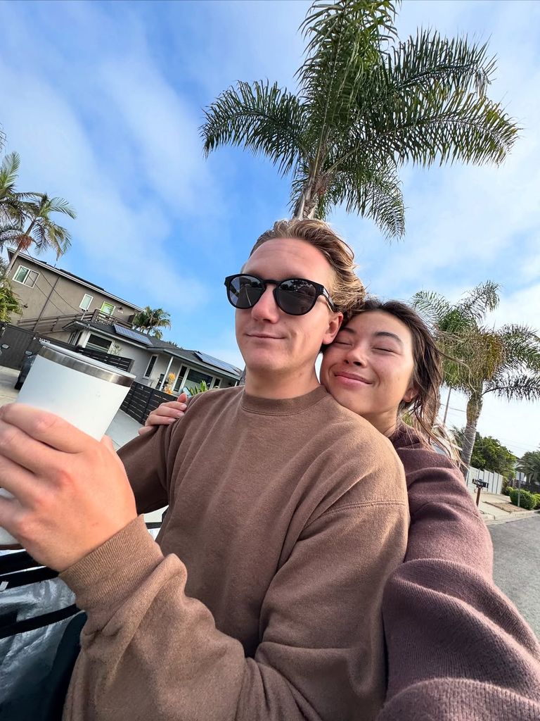 Hailey Langland serre Red Gerard dans ses bras. Red porte des lunettes de soleil et porte une tasse