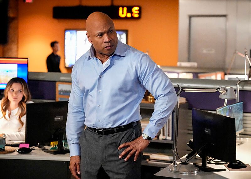  man in blue shirt with hand on hip standing in office