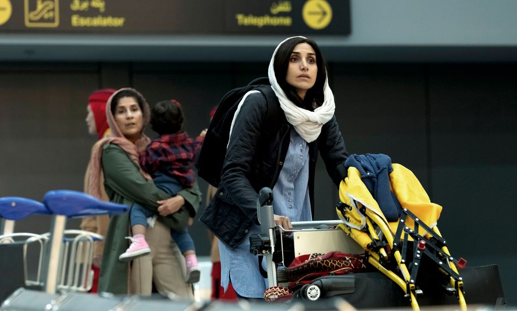 A photo of a woman wearing a white headscarf pushing luggage