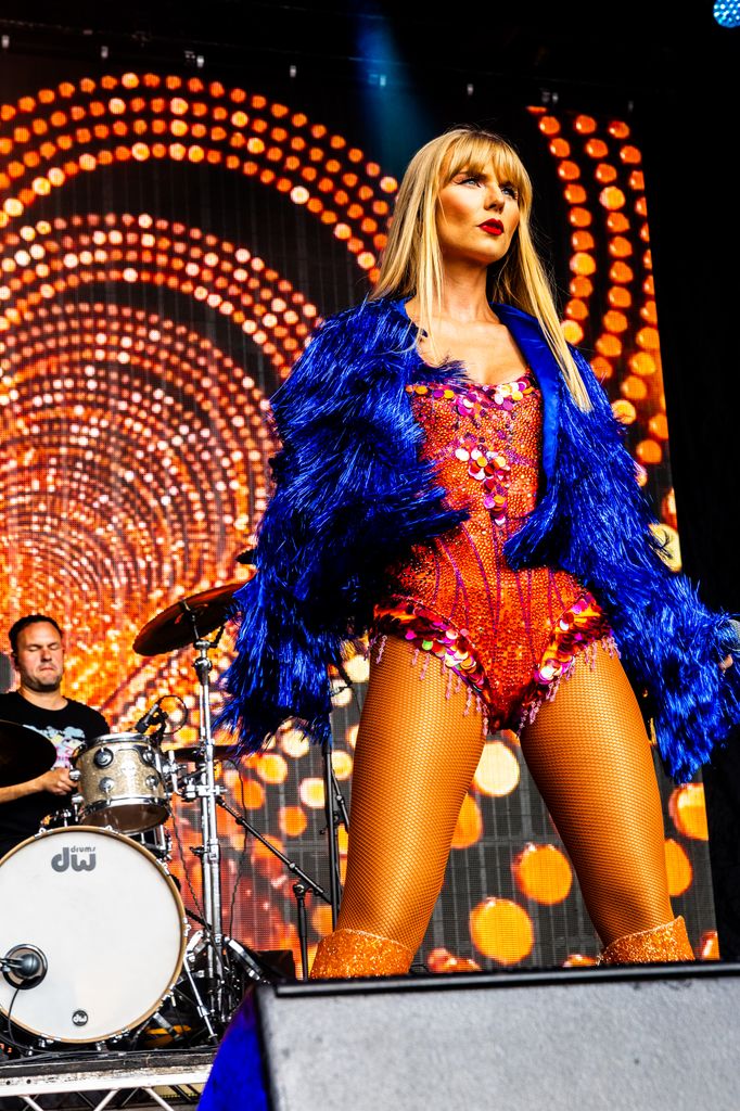 Taylor Swift doppelganger on a stage dressed in red sequinned leotard and dressy blue jacket