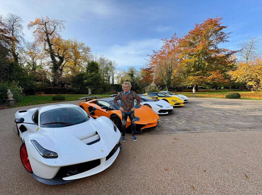 man posing alongside five sports cars