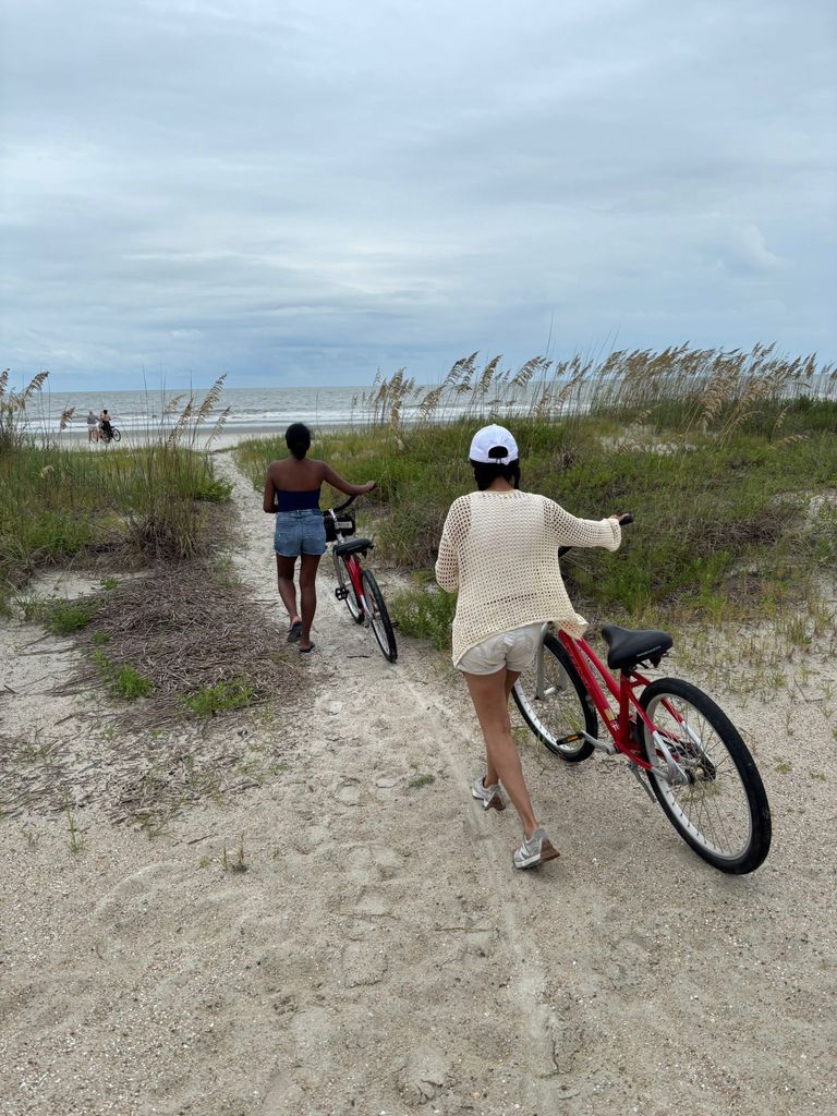 Two woman pushing their bikes along the sand at the beach 
