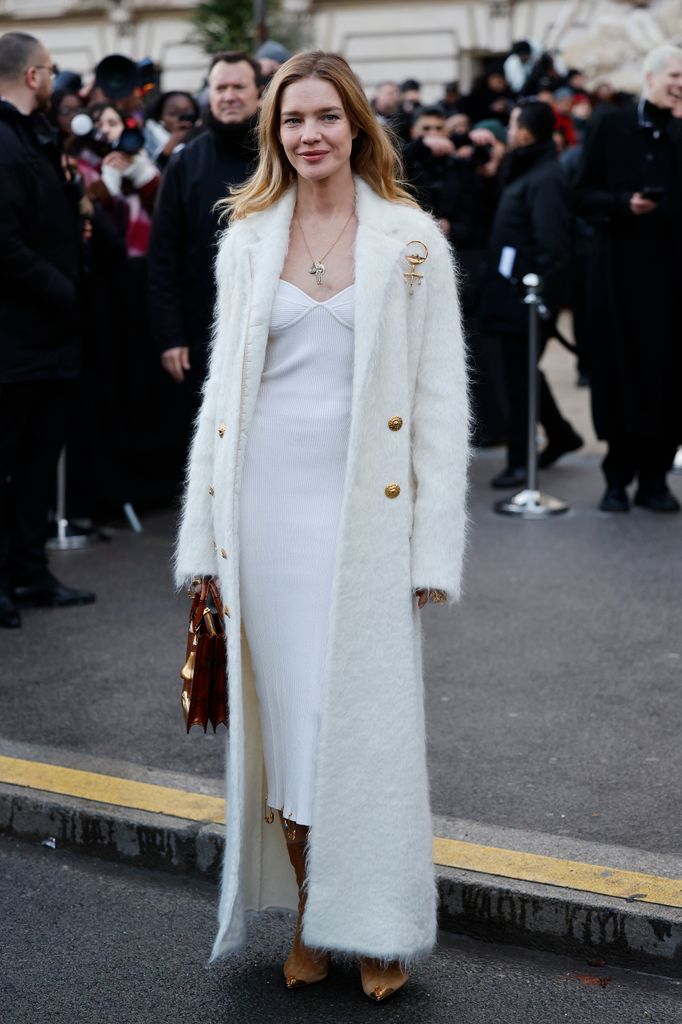 Natalia Vodianova wears a luxurious white fluffy coat layered over a ribbed midi dress with gold-accented boots created a winter wonderland look. The vintage-inspired bag sealed the effortlessly chic vibe.