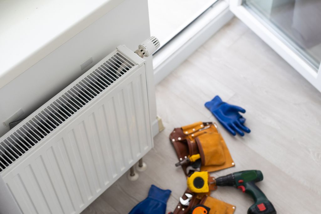 White radiator with gloves and tools on the floor next to it