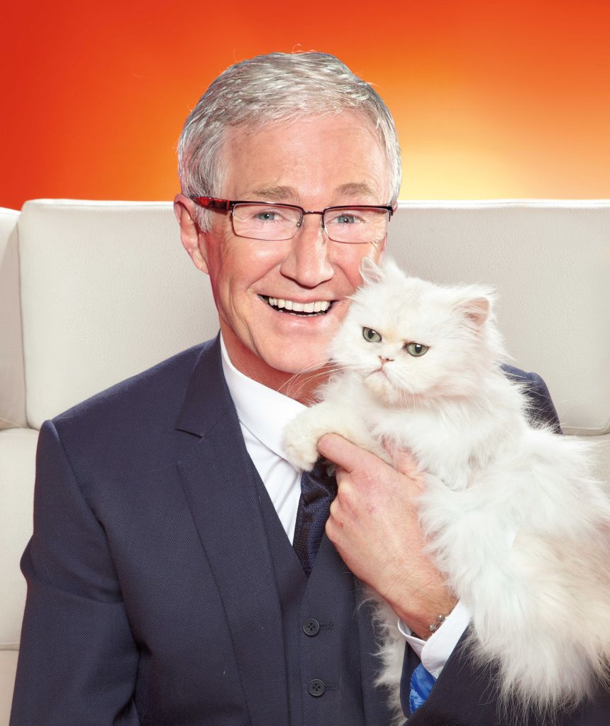 Paul O'Grady smiling whilst holding a cat