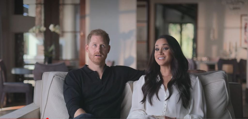 Harry and Meghan sit on a sofa