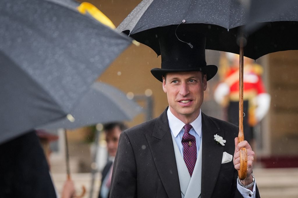 Britain's Prince William wearing top hat and sheltering under umbrella 