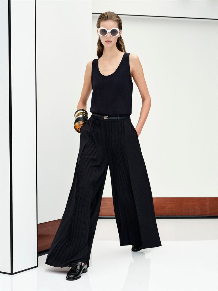 Max Mara Pre Fall 26 runway model wearing a black tank top and wide leg black trousers