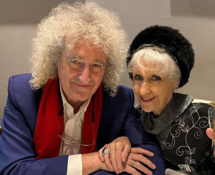 Brian May sitting with Anita Dobson